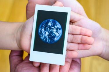 Hands holding polaroid of the earth